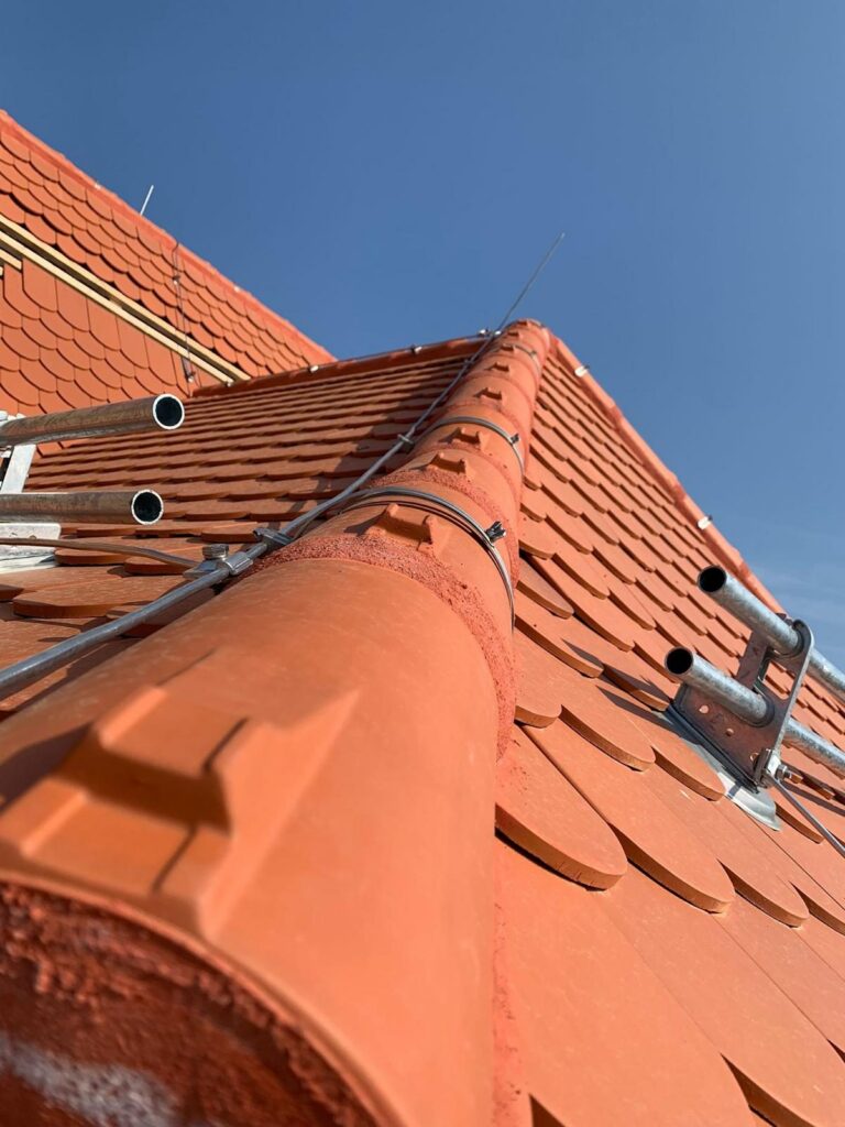 Rotes Biberschwanzdach mit Gratziegeln, Schneefangrohren und Blitzschutzleitung