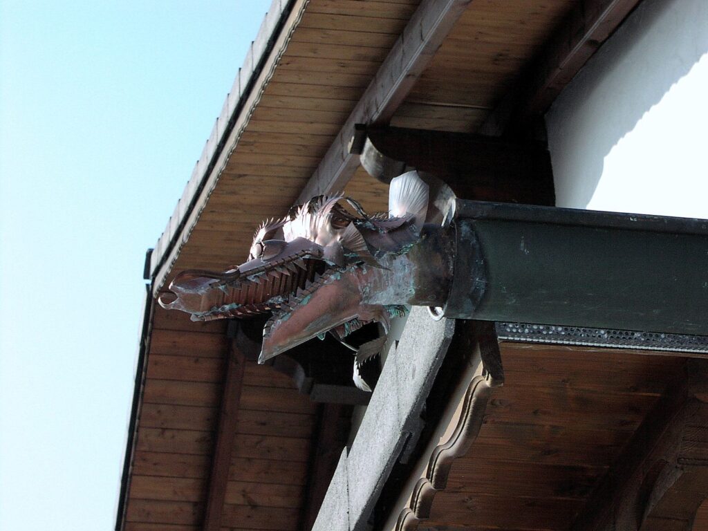 Wasserspeier in Form eines Drachenkopfs aus Kupfer am Ende einer Dachrinne